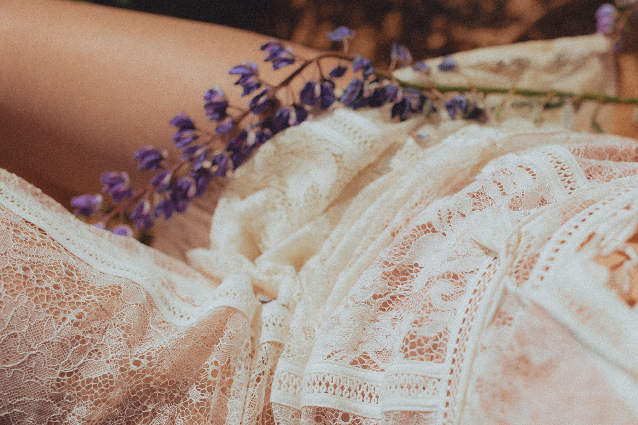 Elegant close-up of intricate lace fabric paired with delicate purple flowers.
